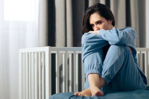 Woman sitting next to crib