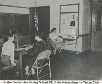Black and white photo of vision technician giving school child the Massachusetts vision test