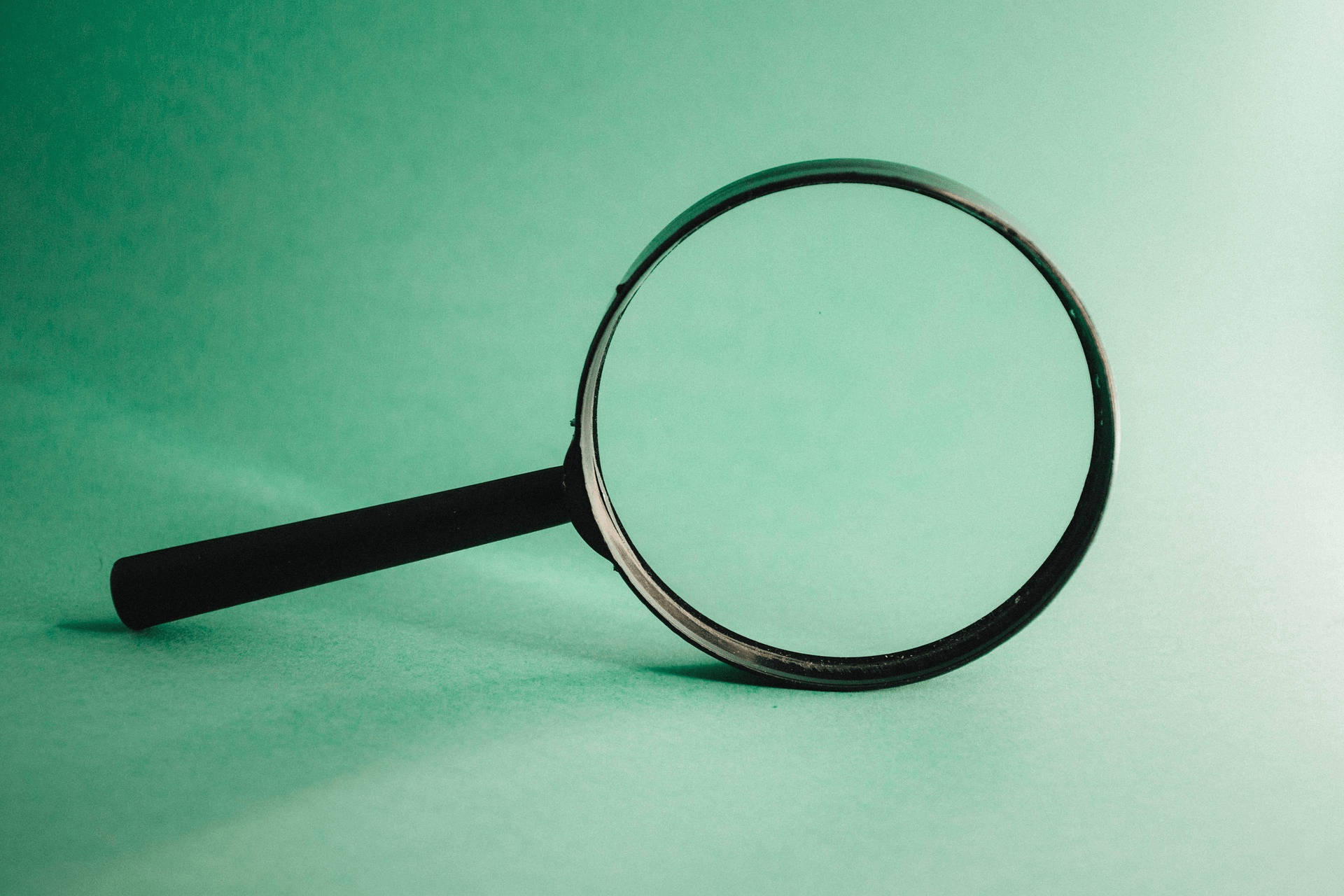 hand-held magnifying glass against light green background
