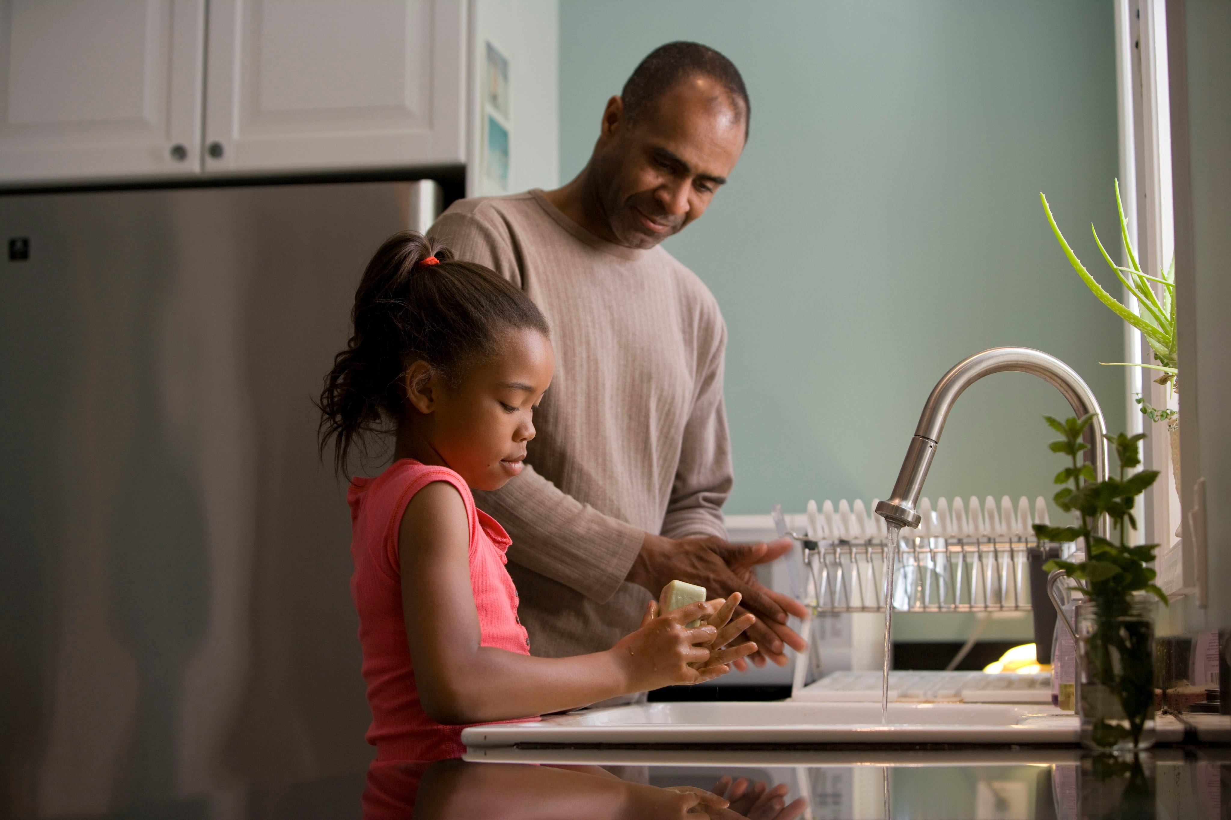 Photo of a man and a girl at the sink washing the dishes.