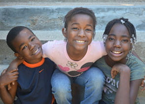 Photo of three children smiling.