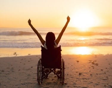 Rearview of person in a wheelchair on a beach