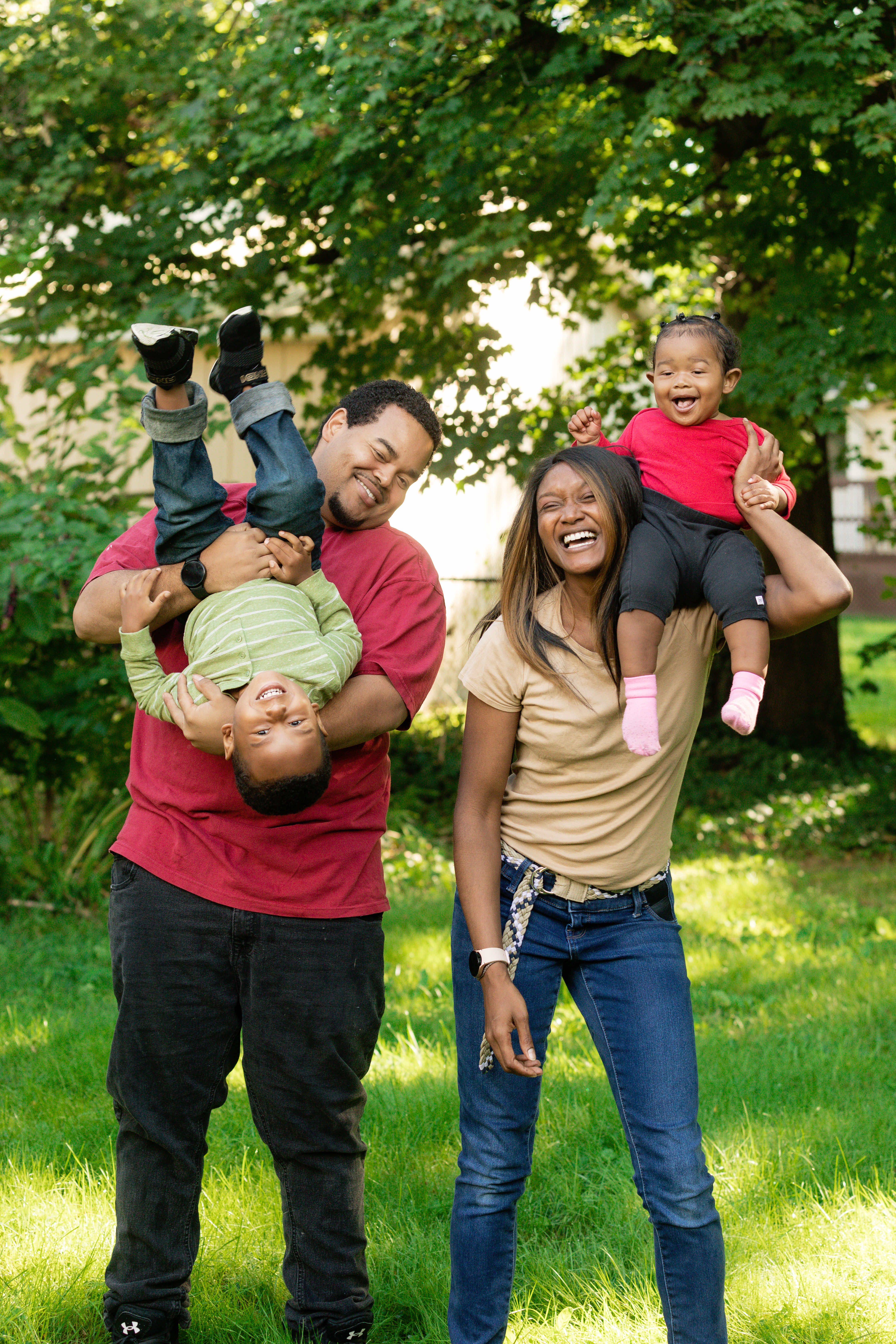 Man Holding Kid Upside Down and Woman Holding Child on Shoulder