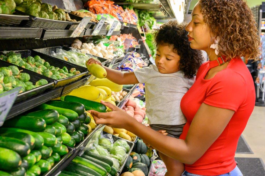 Mom showing child fresh fruits and vegetables