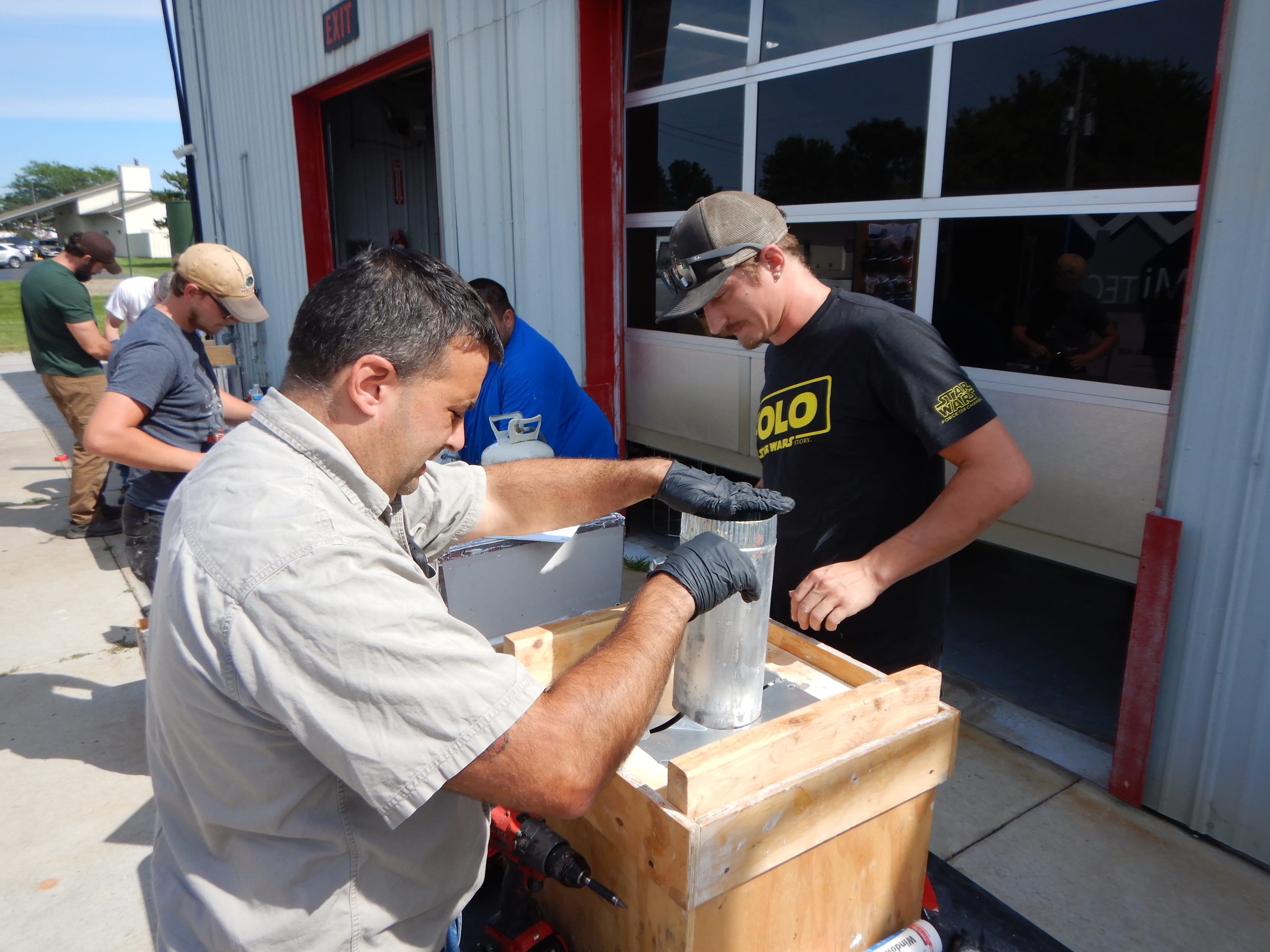 Group of weatherization workers air sealing props outside