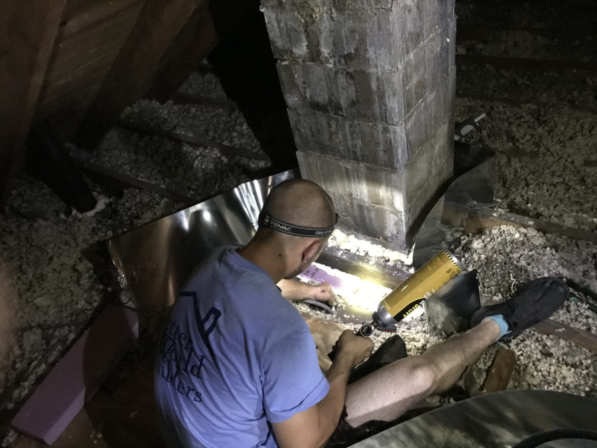 Weatherization worker air sealing near chimney