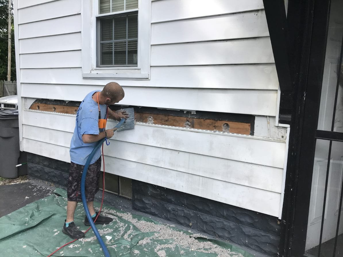 Weatherization worker installing wall insulation