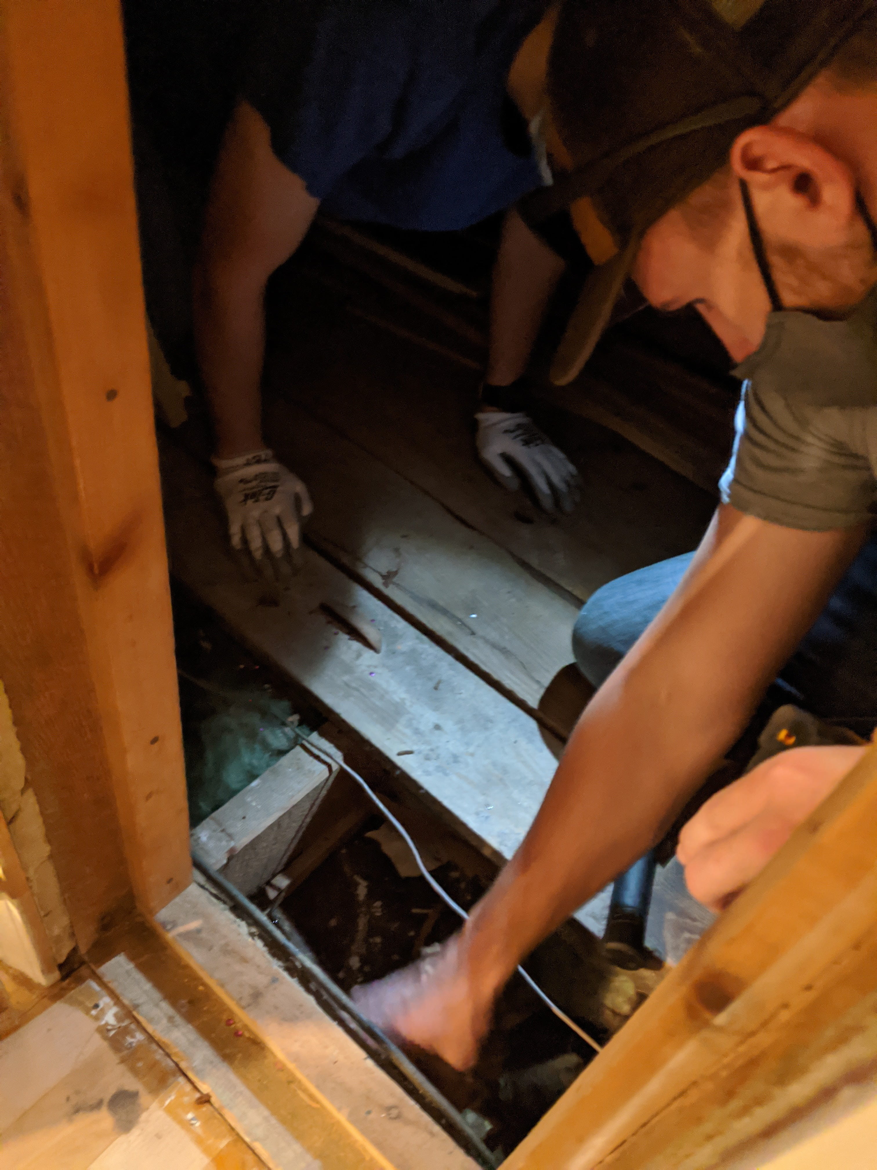 Weatherization workers air sealing the attic knee wall