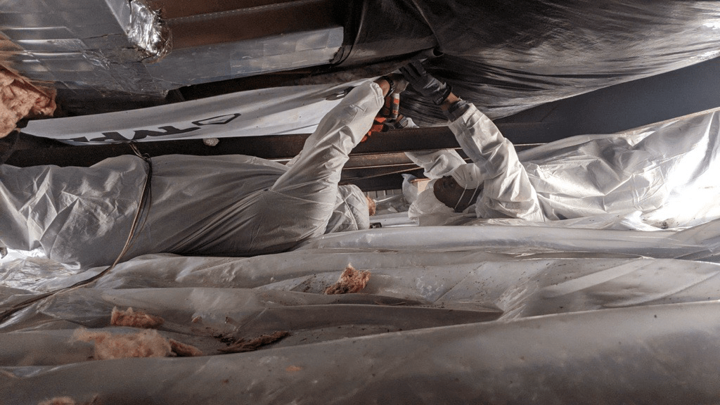 Weatherization workers repairing a mobile home underbelly