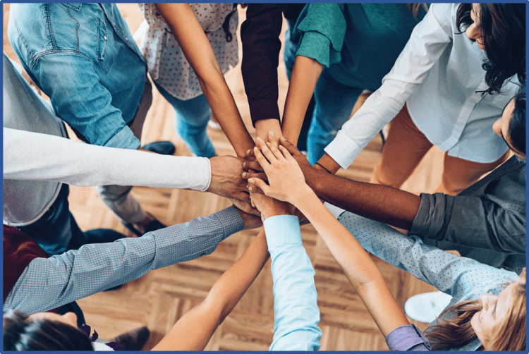 People in a circle with hands joined in the middle
