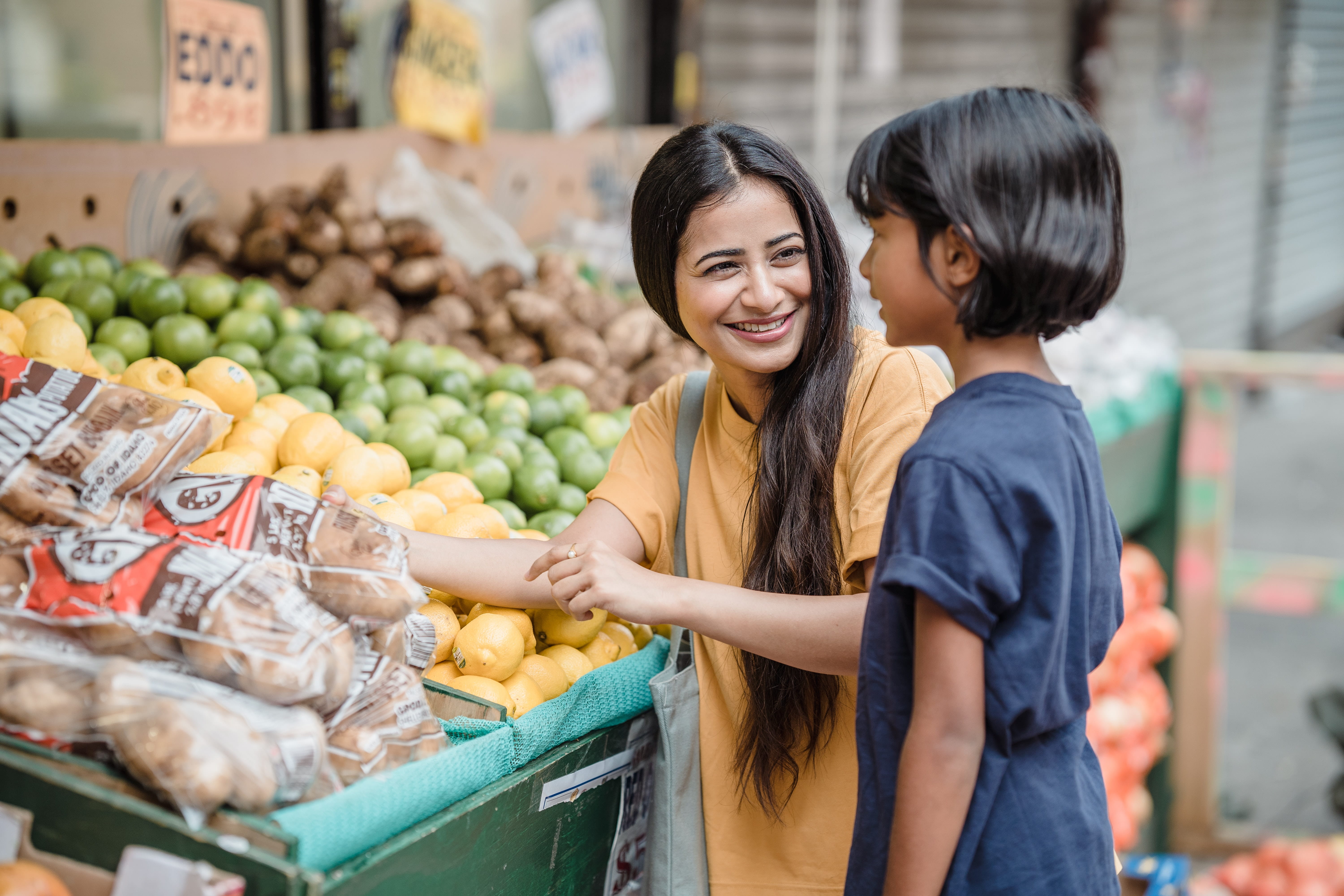 mom and son looking at produce in a grocery store