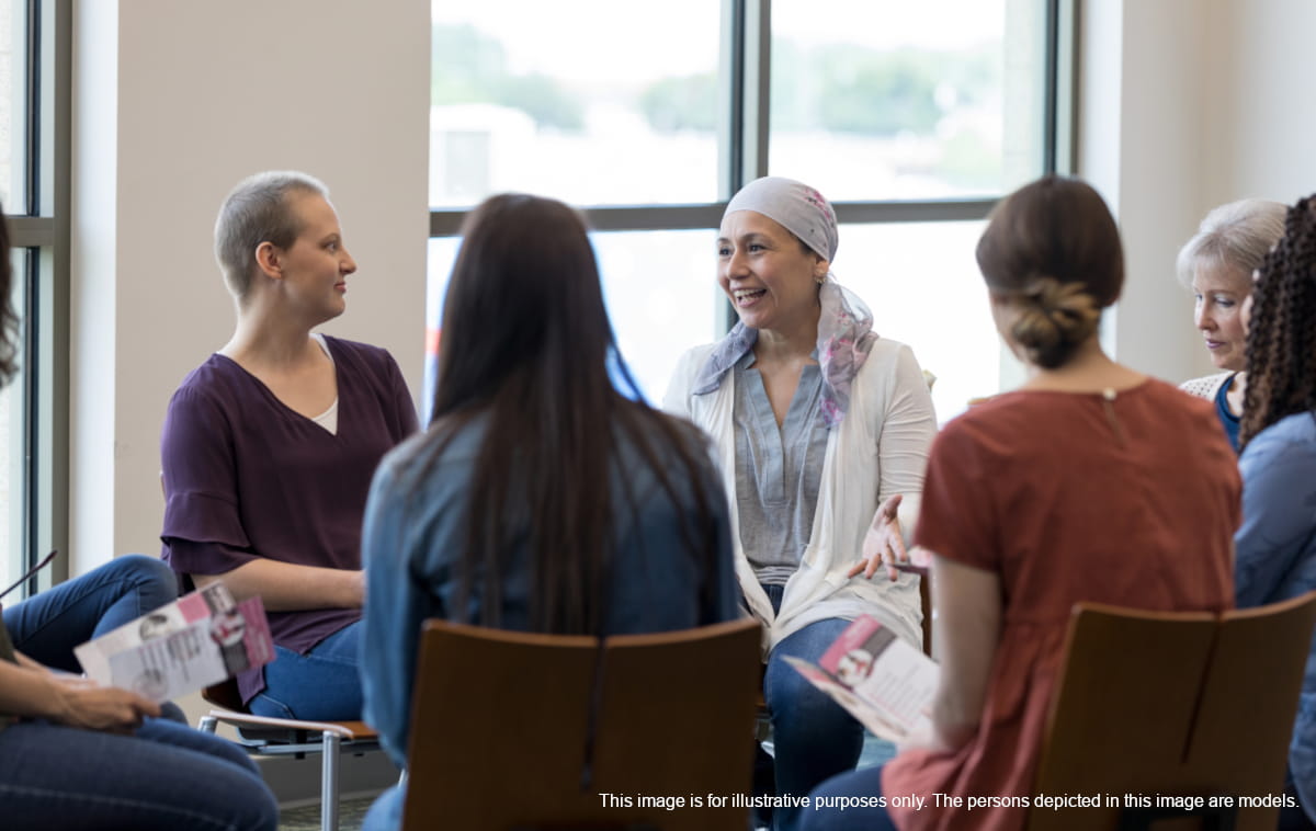 Women of varying ages and ethnicities seated in circle and listening as one member of the group talks