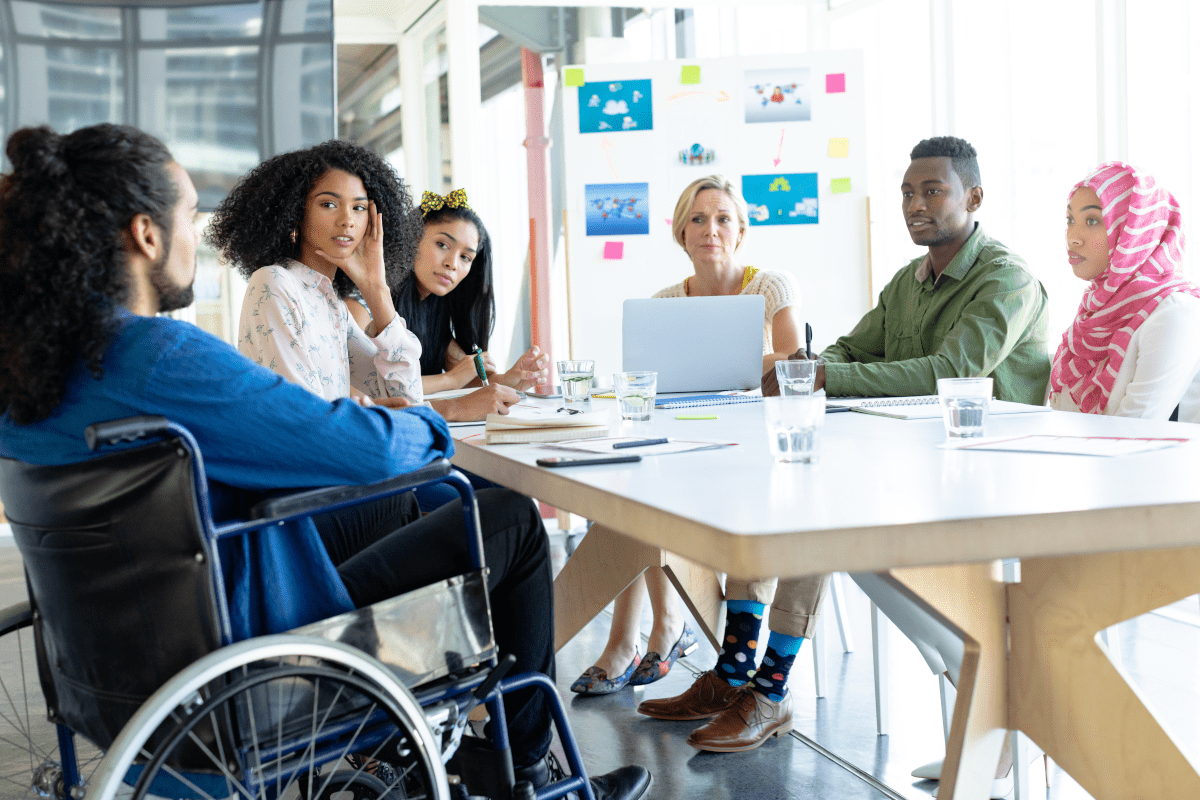 Diverse group of younger business people seated around a conference table and talking