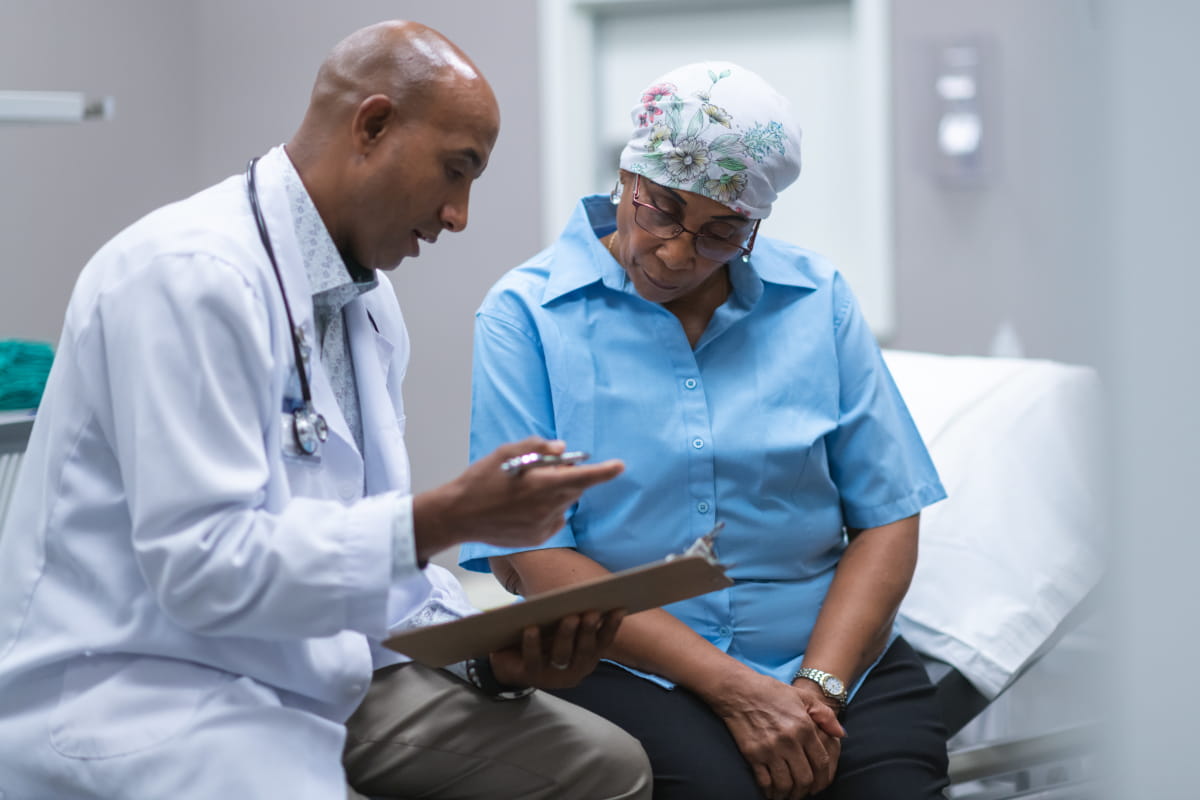 Male doctor (seated) discussing test findings with female patient (also seated)