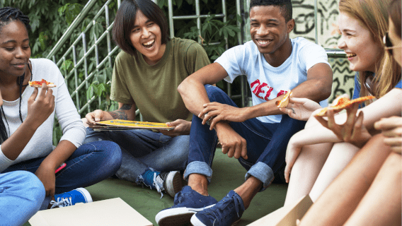 Teenagers sitting in a grassy area with schoolbooks