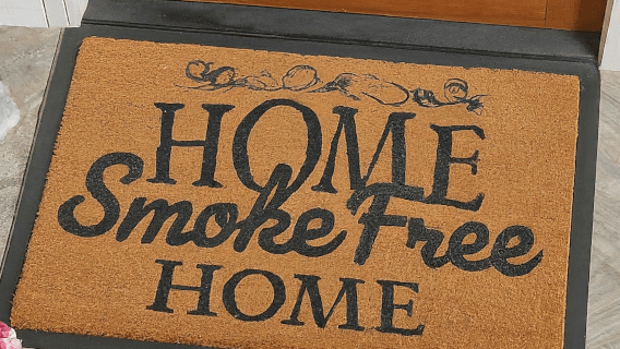 brown outside welcome mat in front of brown wooden door; mat reads "Home, Smoke-Free Home" 