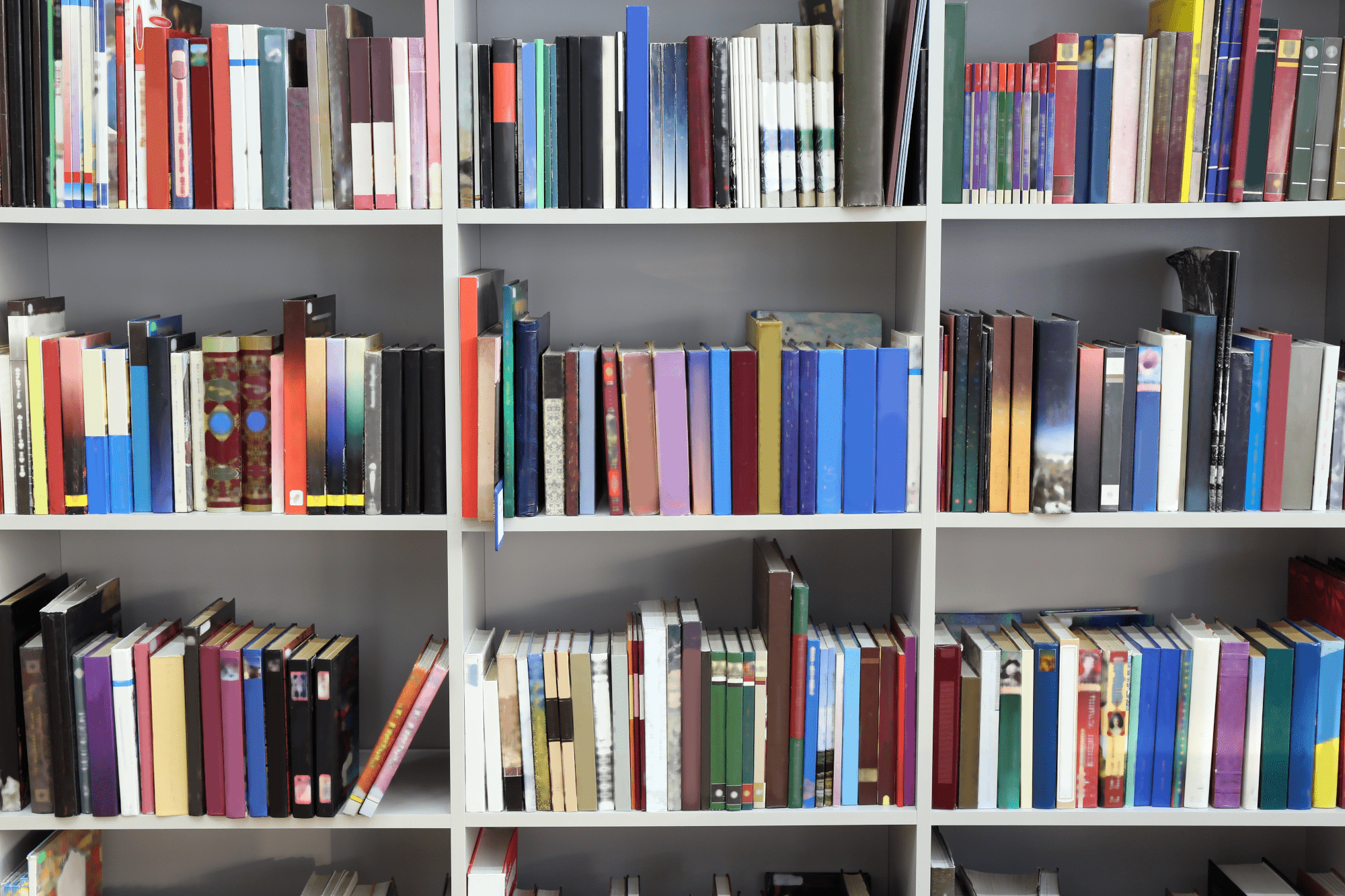 Variety of books on multiple white shelves in a library