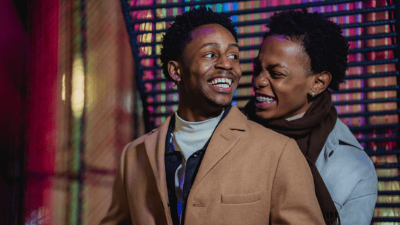 Cheerful black couple embracing and laughing happily 