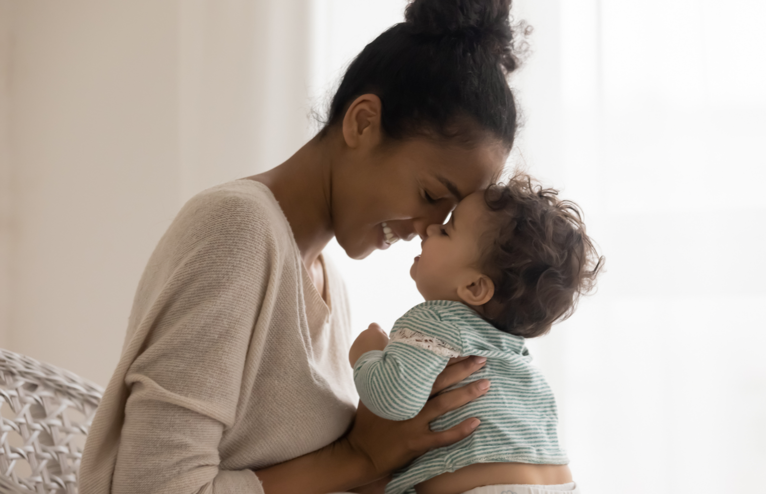 Mom lovingly holding a baby while smiling and touching faces