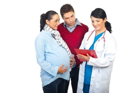 Doctor pregnant person and father conversing