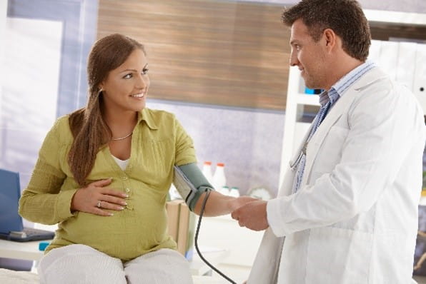 Doctor taking pregnant persons blood pressure