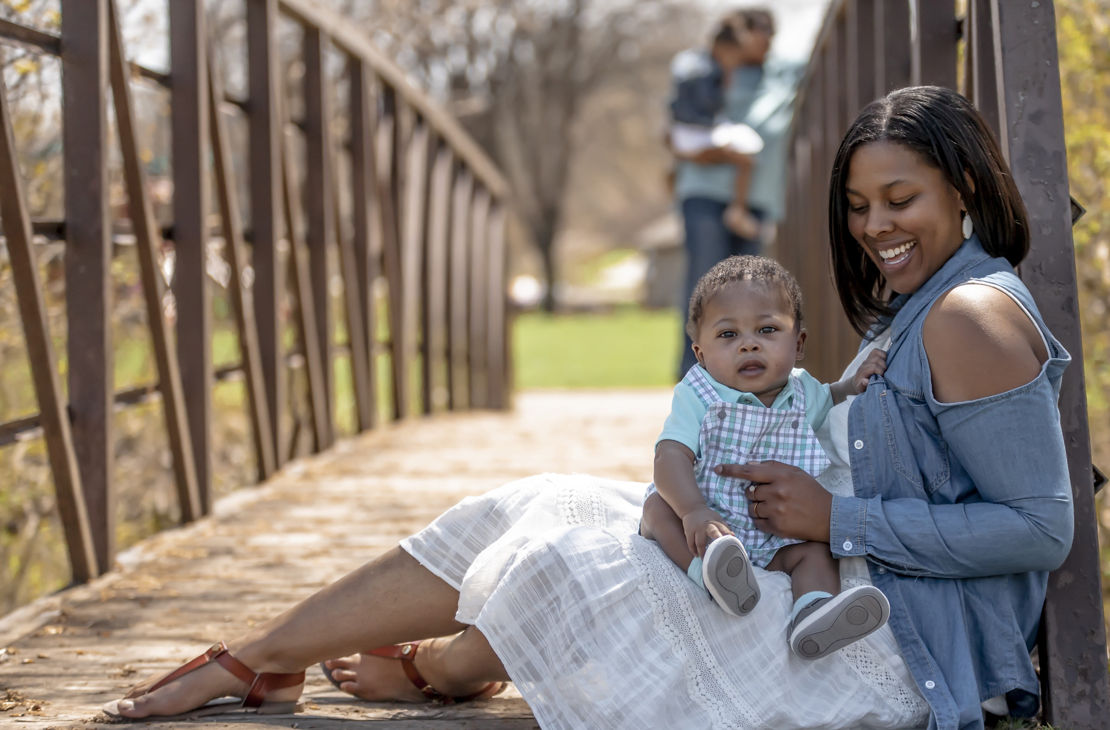 Family with little baby sitting on a bridge
