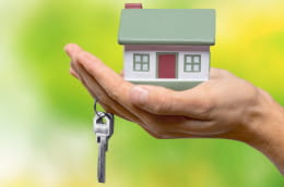 Outstretched hand holding a toy house and a key