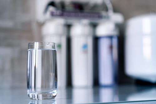 Glass of water sitting in front of a drinking water filtration system