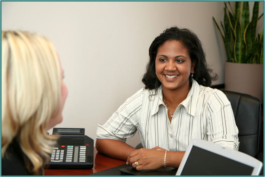 two people on either side of a desk smiling at each other