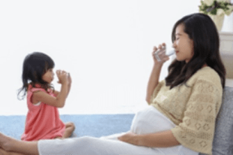 Mother and young daughter drinking water