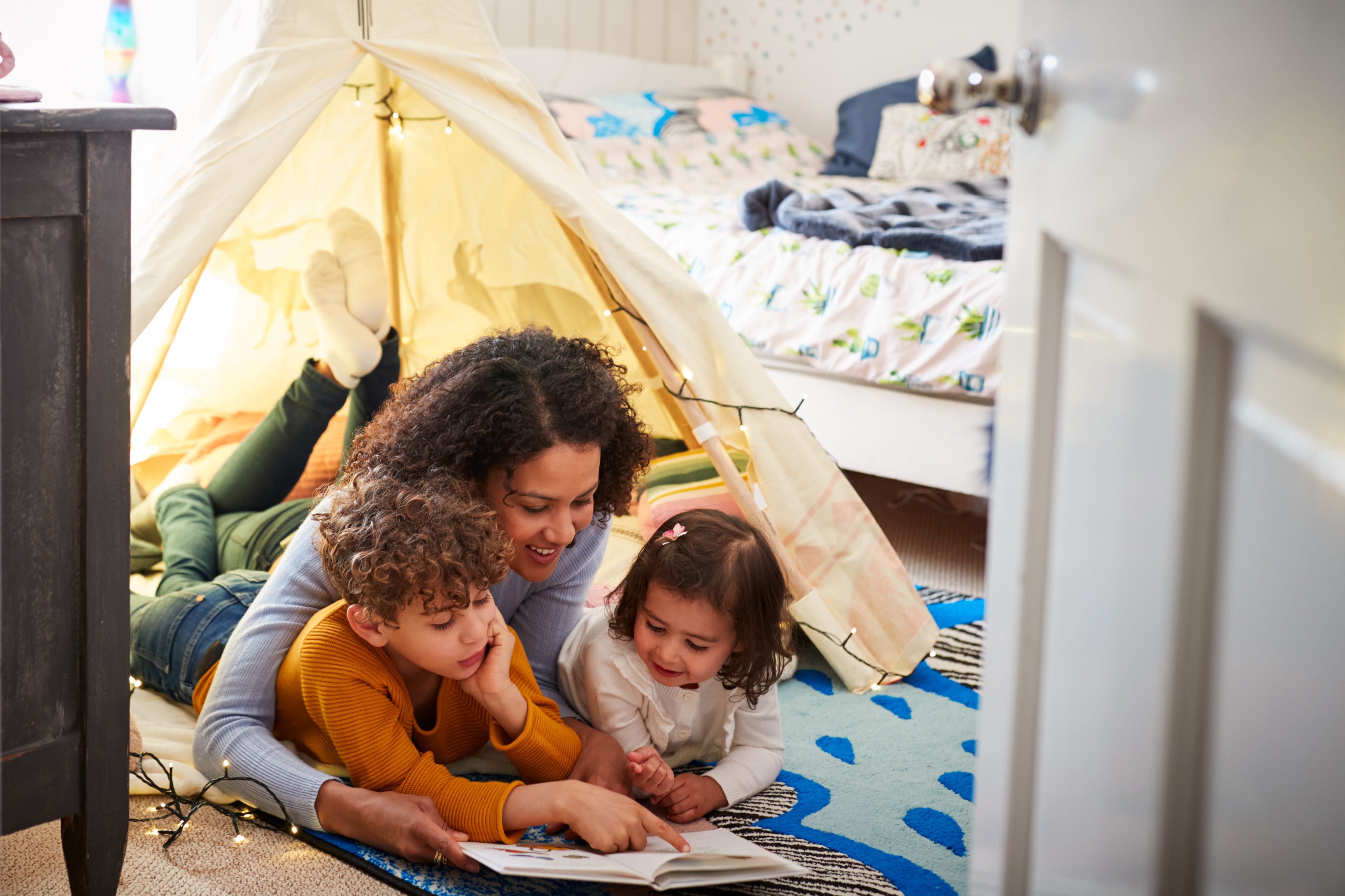 Woman reading to two children in a cozy bedroom
