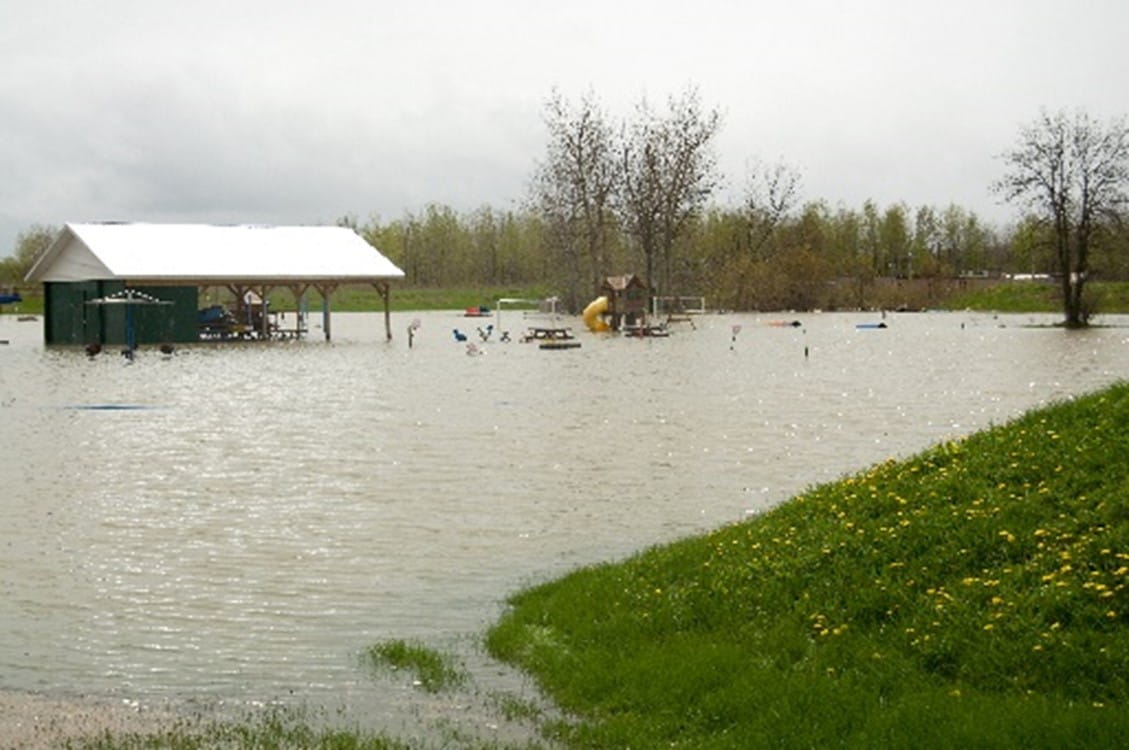Flooded public park. A picnic shelter and children's playground equipment are partially submerged in water.