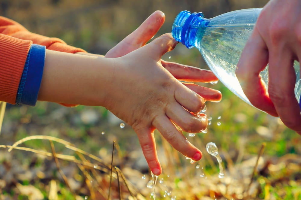 Child washing their hands using bottled water
