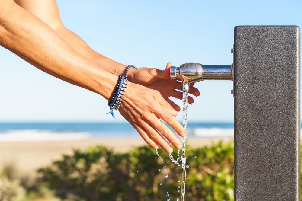 Hands being washed under an outdoor spigot