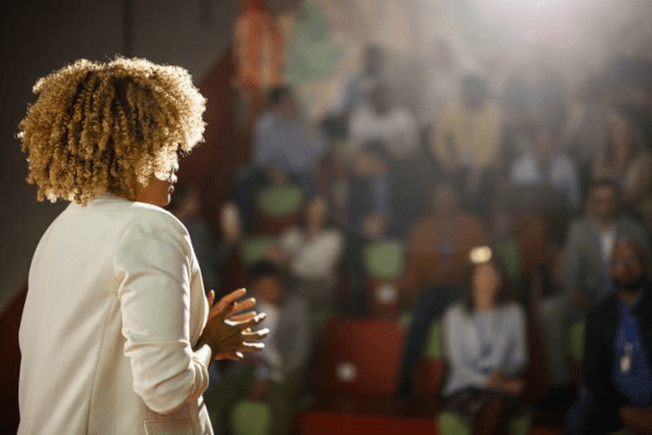 Woman giving a presentation before a large audience