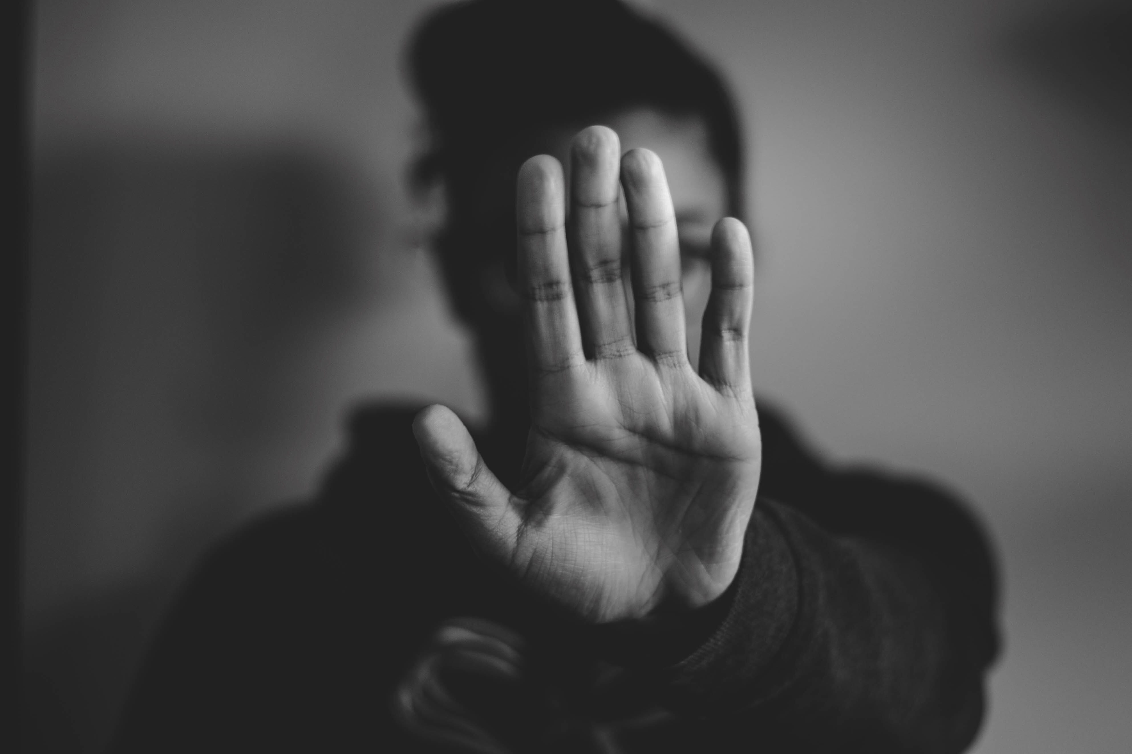 Black and white photo of a woman holding her hand out in front of her in a 'stop' motion.