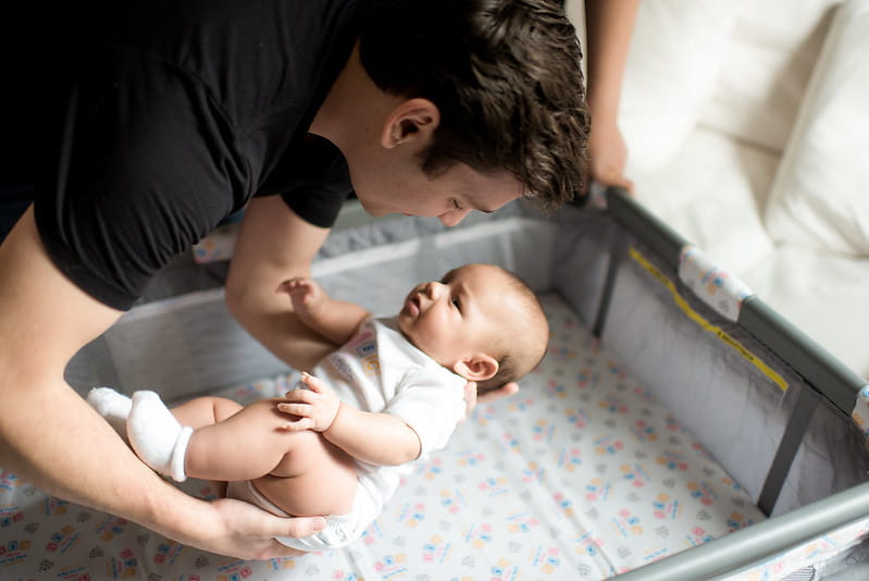 Dad Placing Baby in Crib