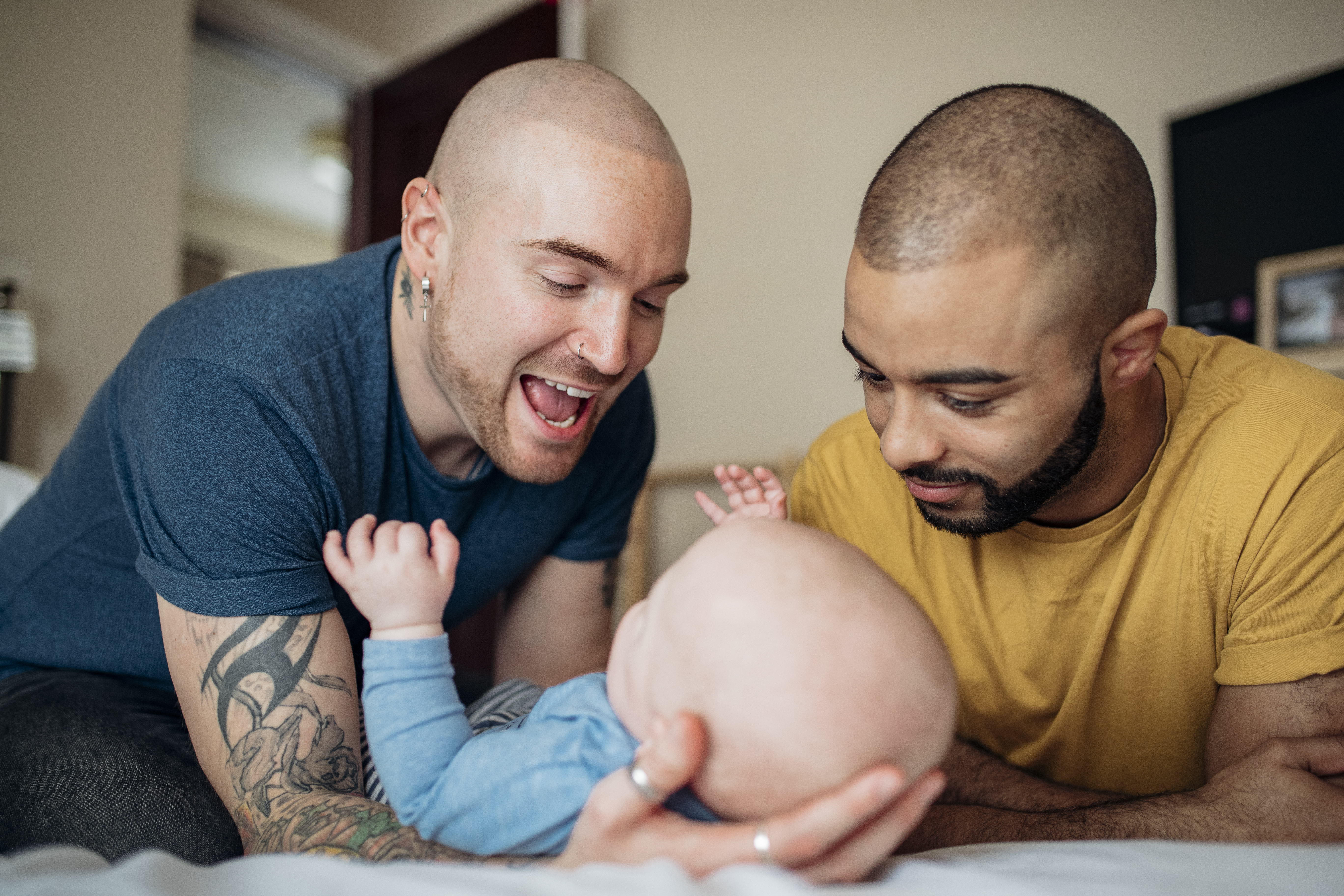Two people smiling at baby one of them is holding