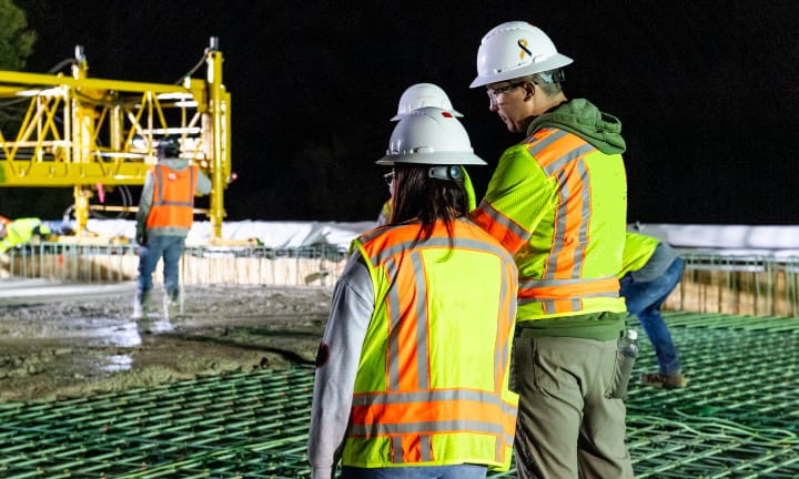 Employees watching as work progresses on an active construction site. 