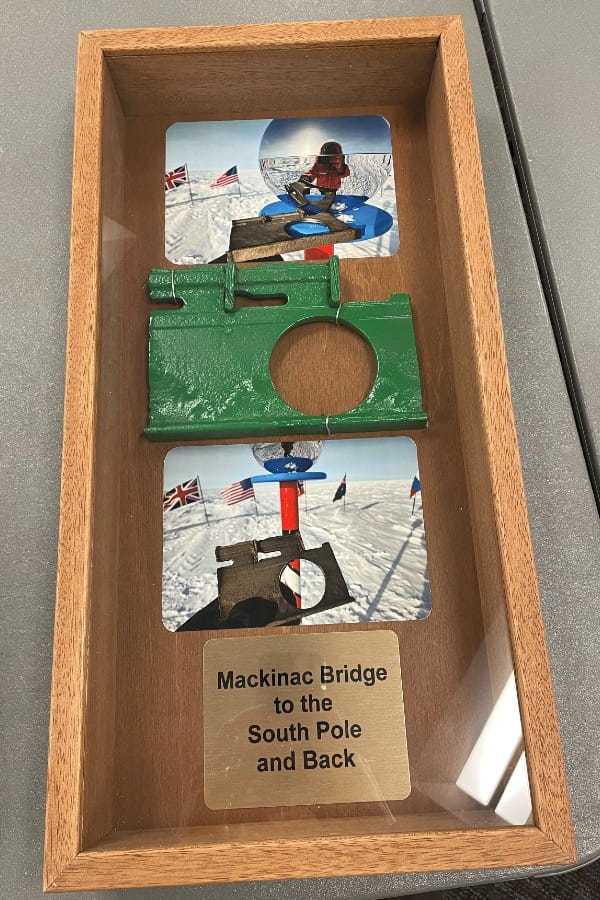 A shadowbox with photos and a piece of the Mackinac Bridge steel used to make the current ceremonial and geographical South Pole markers, presented by Brendan Fisher to the Mackinac Bridge Authority.  