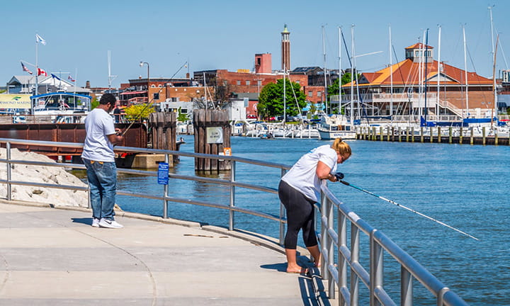 Two people fishing off the edge of a dock