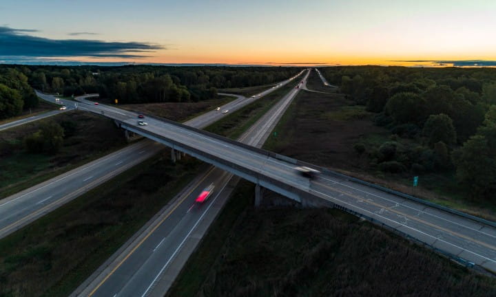 Cars driving down two intersecting freeways in Michigan at sunset.