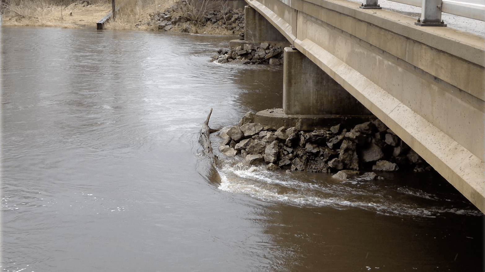 Bridge pier and water flowing under bridge.