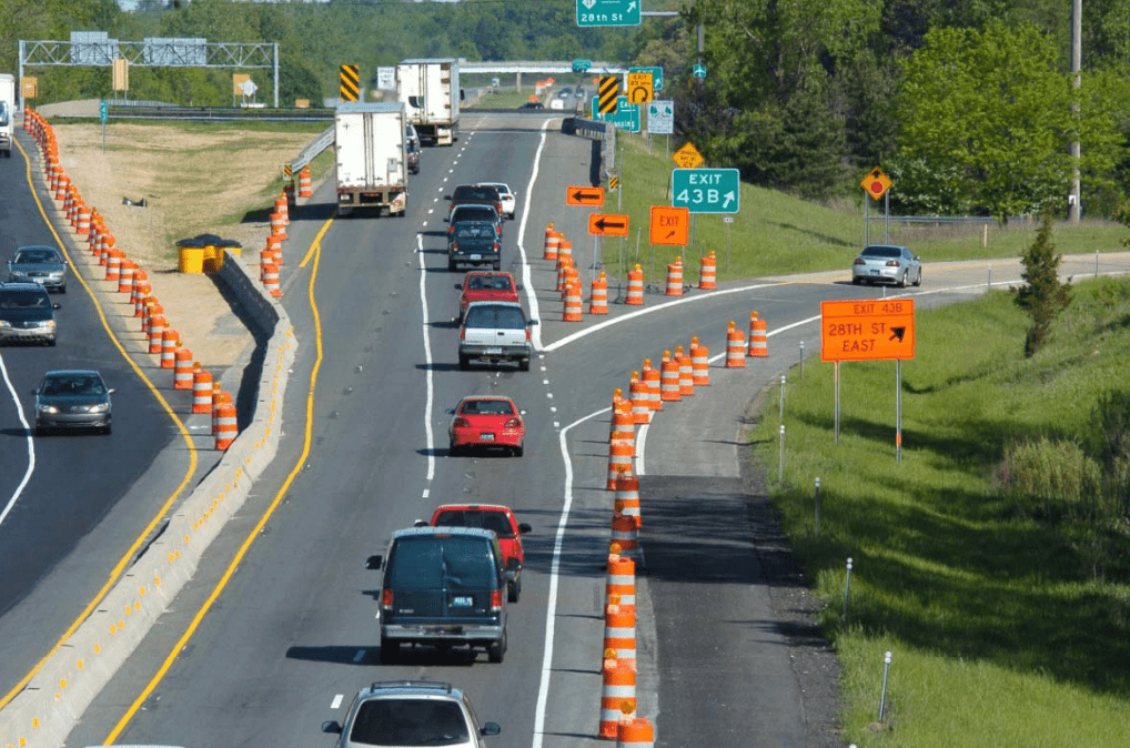 An MDOT worker holds a level against a retaining wall to measure tilt.