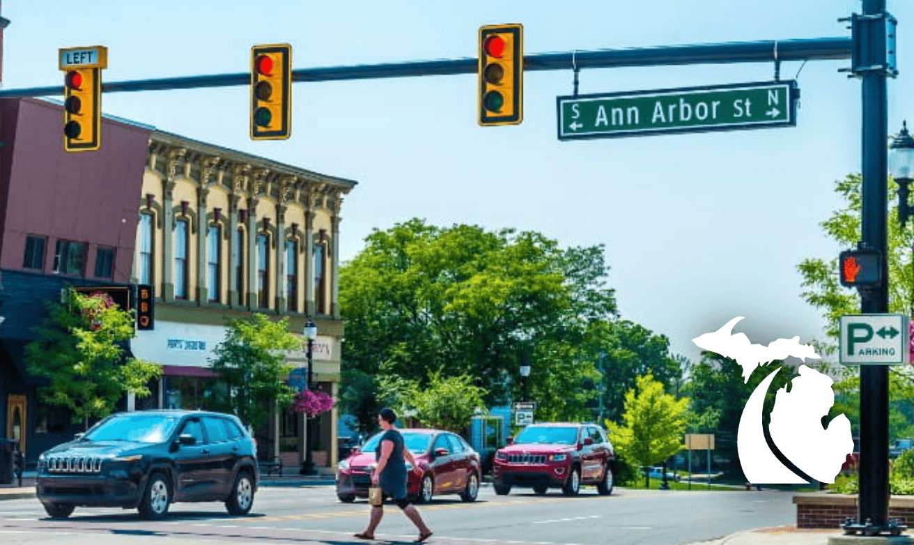 Three traffic signal units mounted to a horizontal bar on an urban street.