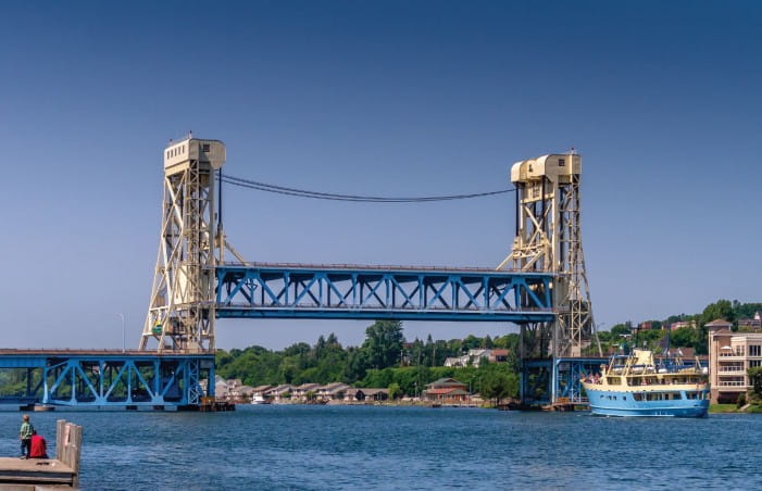 The Portage Lake Lift Bridge between the cities of Houghton and Hancock, Michigan. This vertical-lift bridge has two tower-like structures, and the decked truss segment between the towers can be raised and lowered.