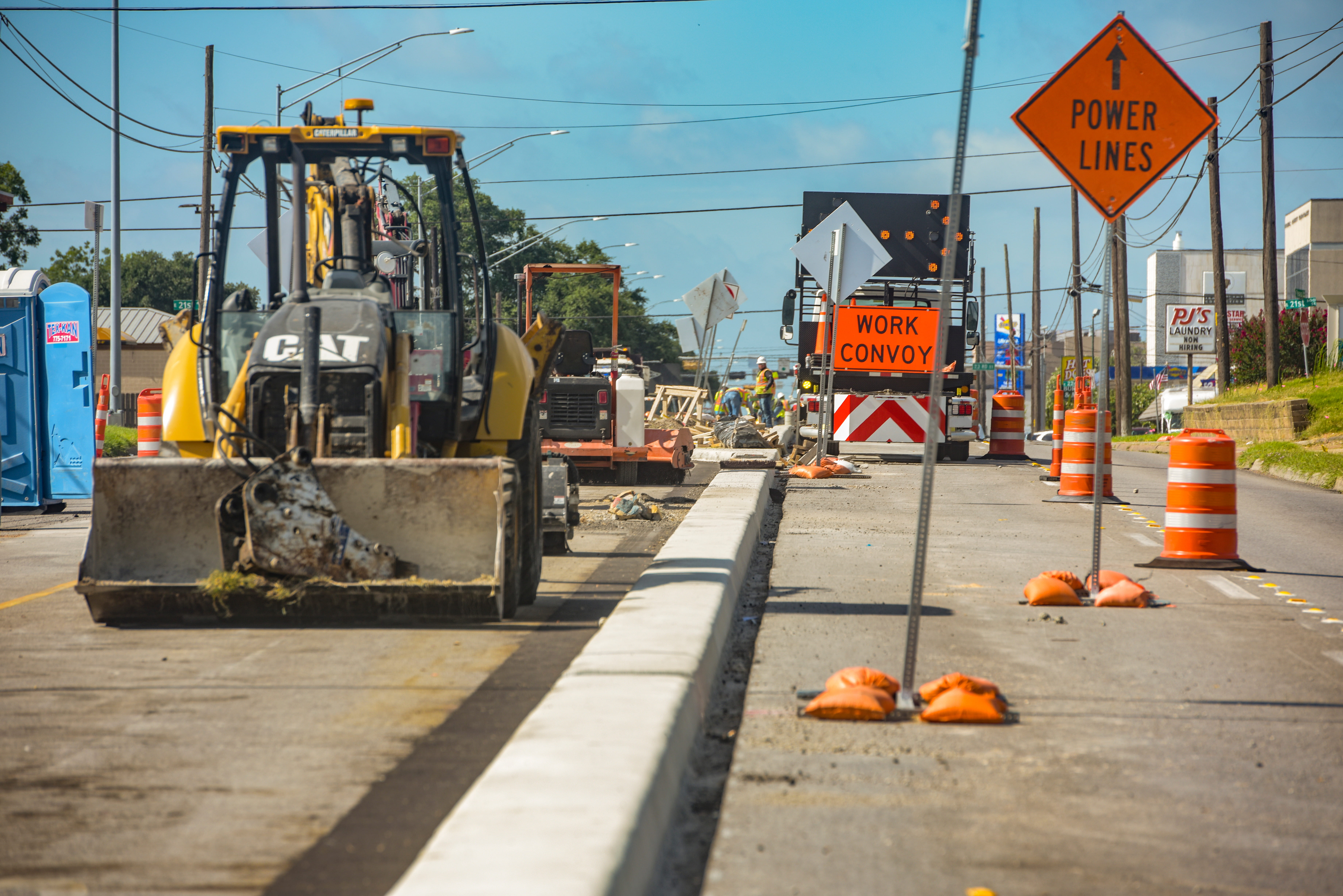 Construction signs and heavy equipment line a road construction site.
