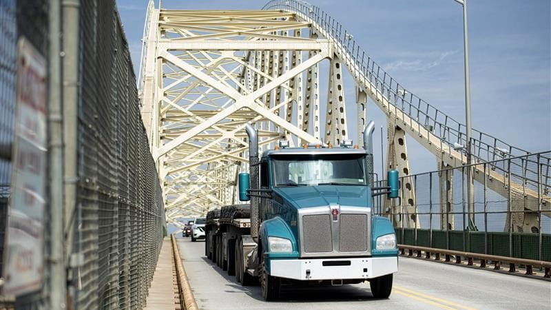 A blue semi tractor trailer crosses over the International Bridge between the United States and Canada.