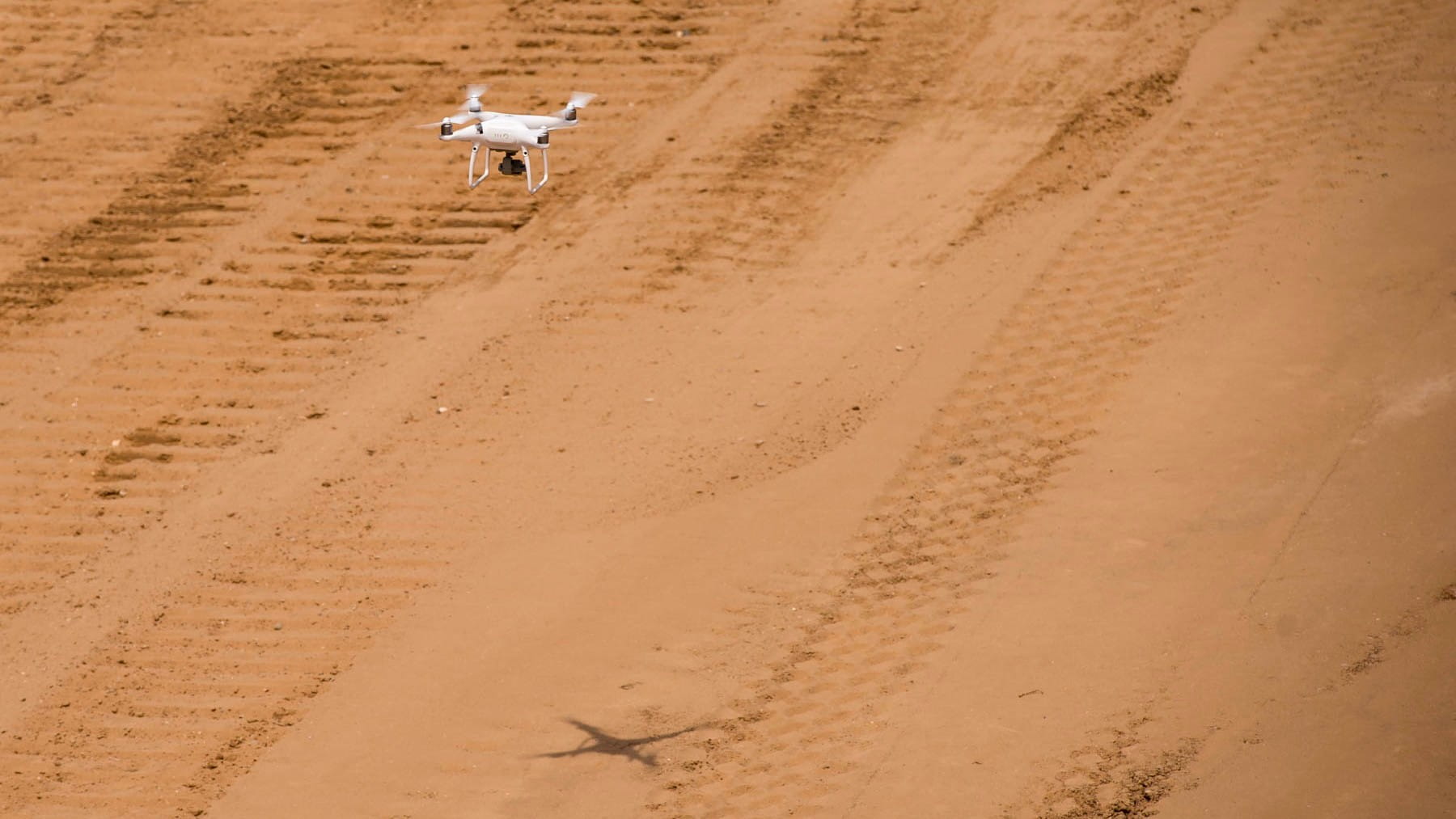 A low-flying drone above a sandy terrain.