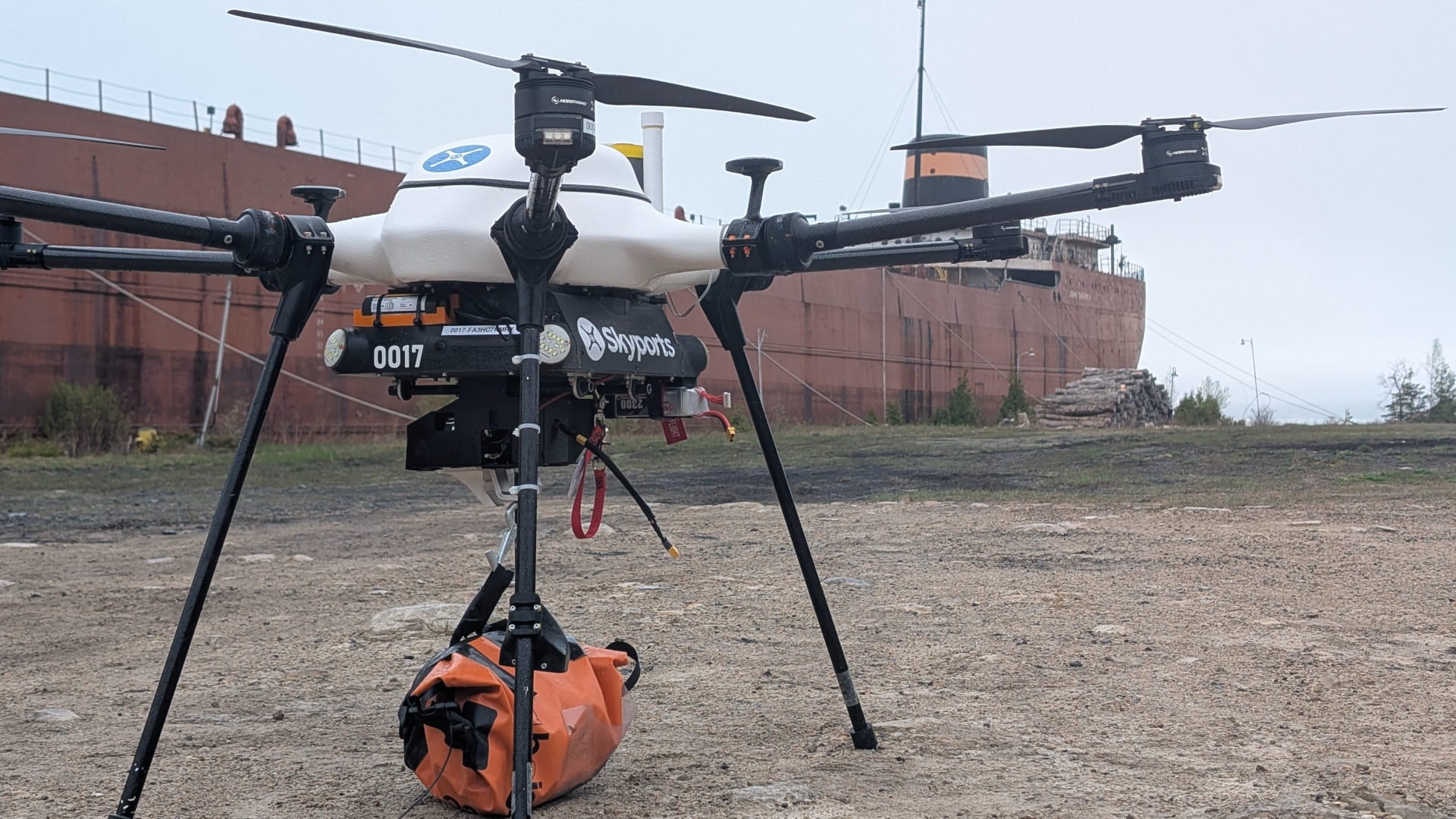 A package delivery drone landed in front of a container ship.